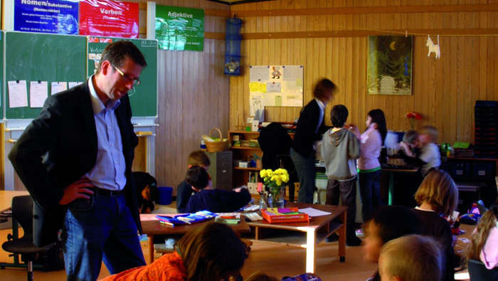 Un profesor ayuda a los alumnos de In der Alten Forst, alumbrada con soluciones de iluminación para colegios de Philips