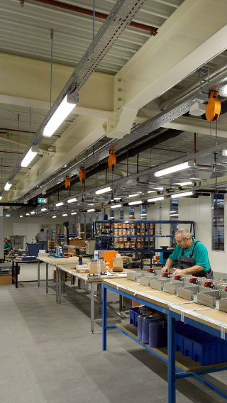 Un empleado trabaja en el área de producción de Venco Campus iluminada brillantemente con la iluminación industrial de Philips