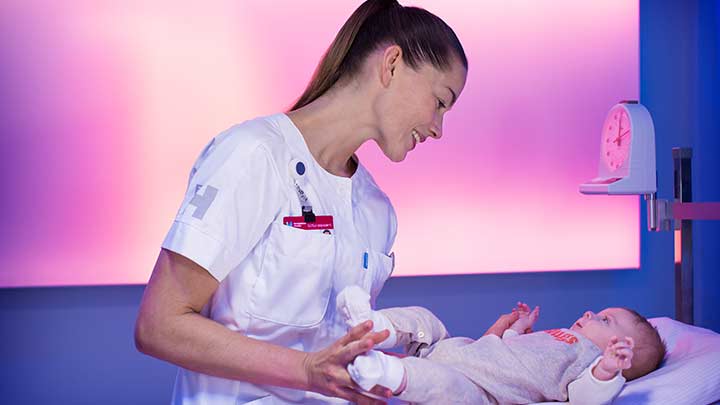 Enfermera pesando un bebé en una sala con iluminación tenue - iluminación para cuidado de la salud